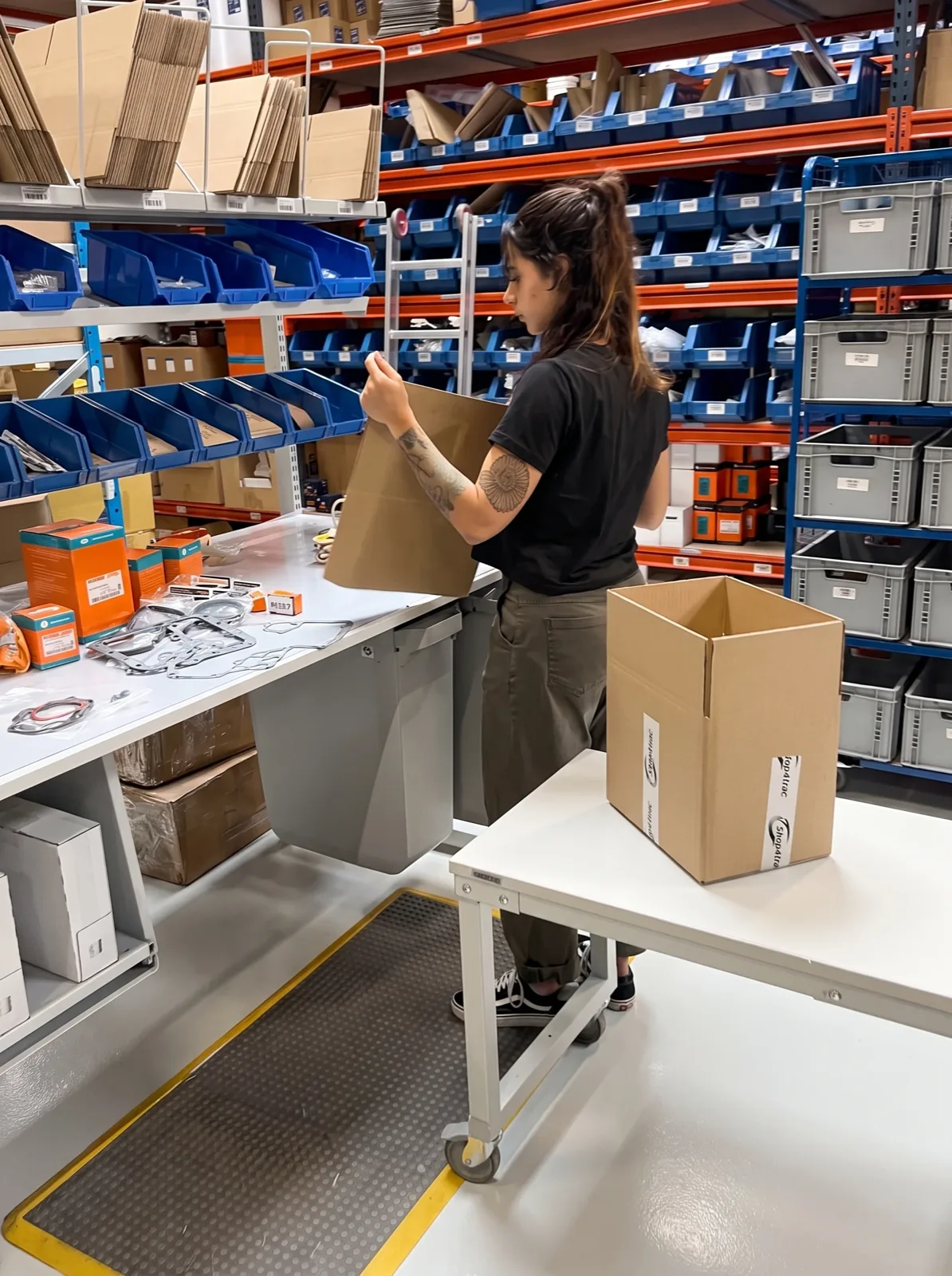 Un membro del team prepara una scatola di spedizione al banco di imballaggio di Shop4Trac
